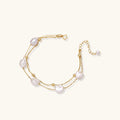 Double-strand gold bracelet with irregular baroque pearls and smooth freshwater pearls on cream background.