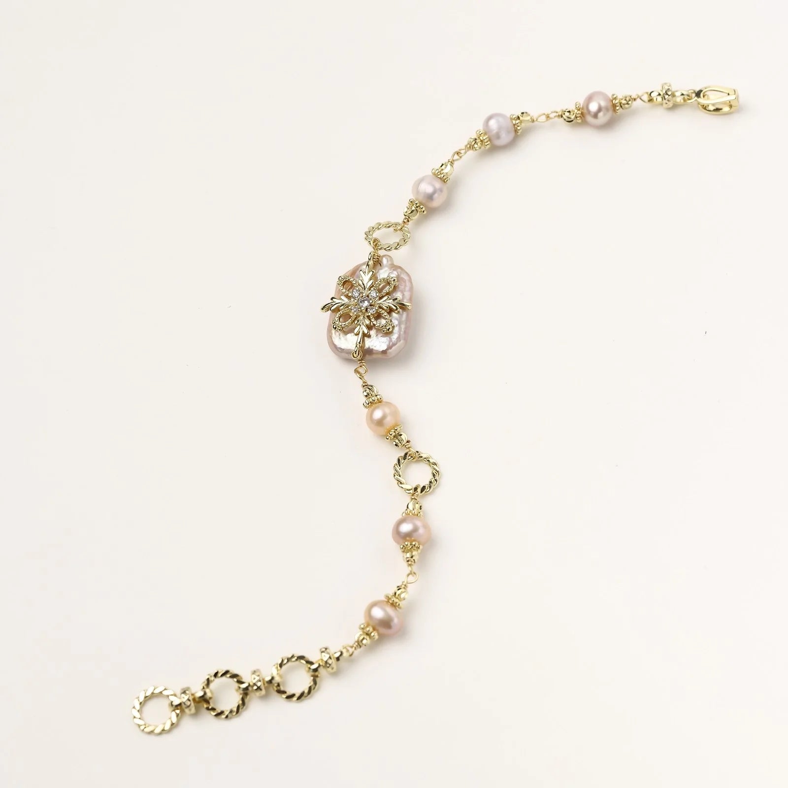Gold-plated bracelet with pink baroque pearl centerpiece, floral connector, and freshwater pearls