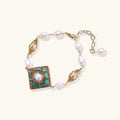 Gold-plated bracelet with baroque centerpiece, turquoise stones, freshwater pearls, and ornate chain links on cream background.