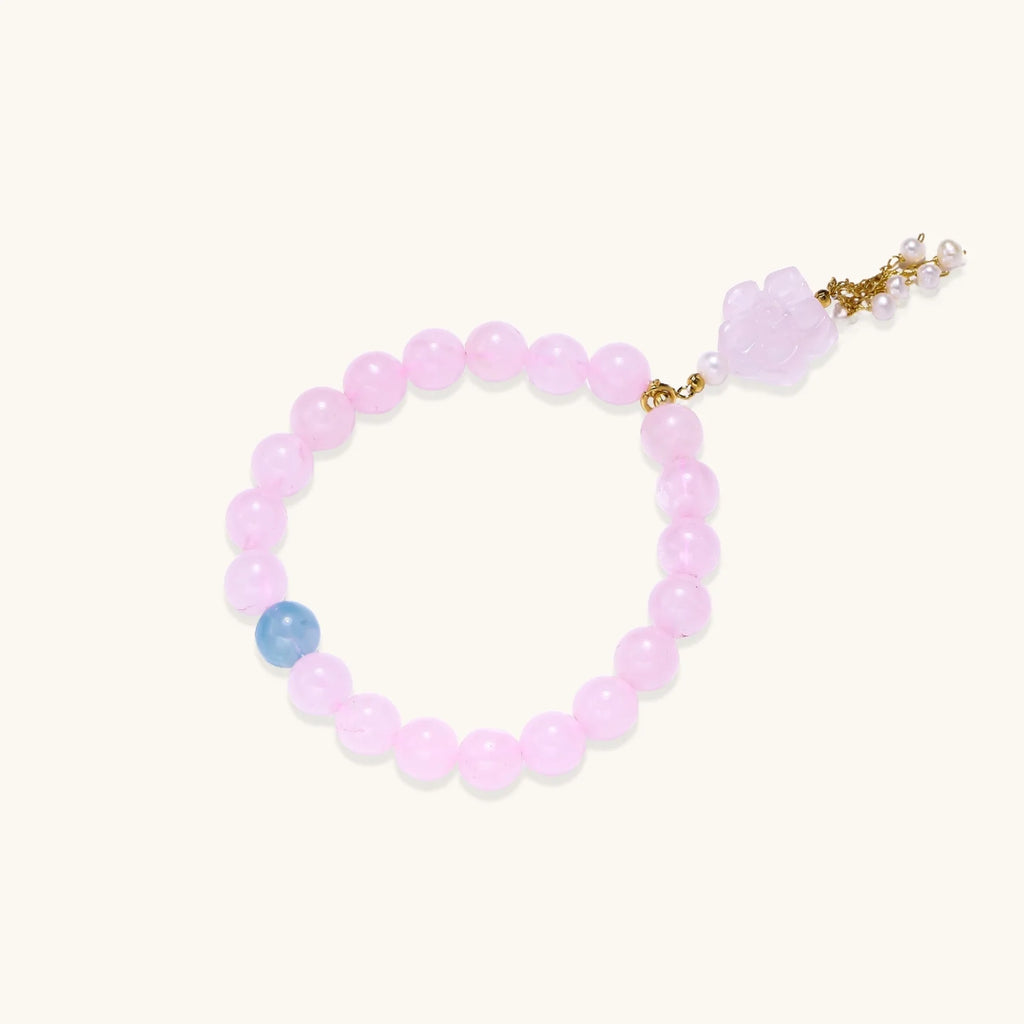 Stretchy beaded bracelet with pink rose quartz, blue aquamarine, carved floral pendant, and pearl tassel clasp.