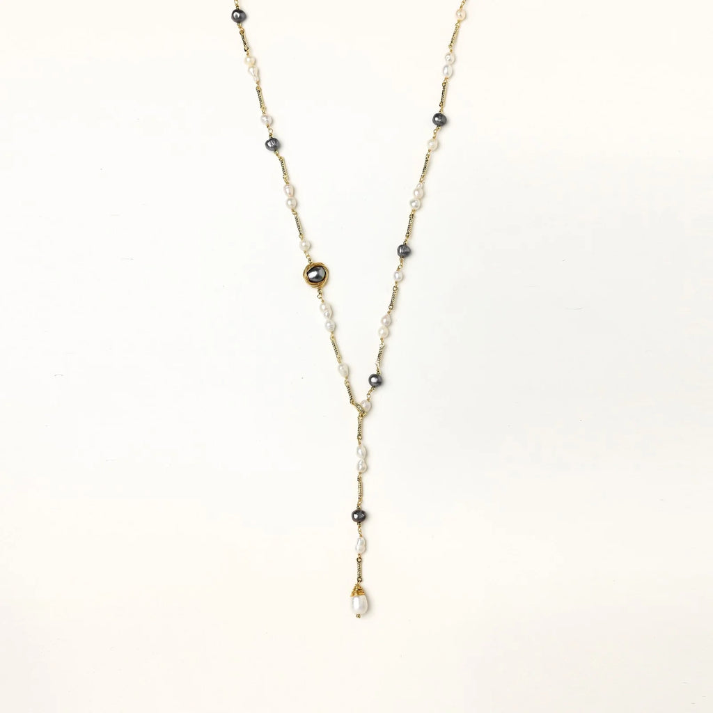 Y-shaped gold-plated necklace with white and gray freshwater pearls on cream background, showing adjustable drop design.