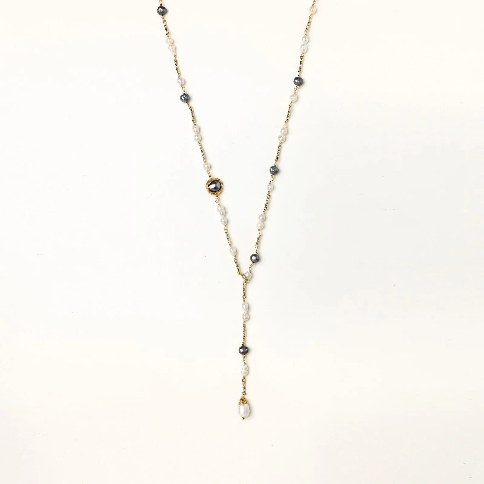 Y-shaped gold-plated necklace with white and gray freshwater pearls on cream background, showing adjustable drop design.