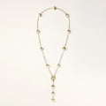 Gold-plated lariat necklace with baroque pearls and textured caps on cream background, showing adjustable Y-shaped design.