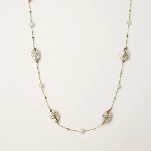 Long gold chain necklace with baroque pearls wrapped in leaf designs and small freshwater pearls spaced along the strand