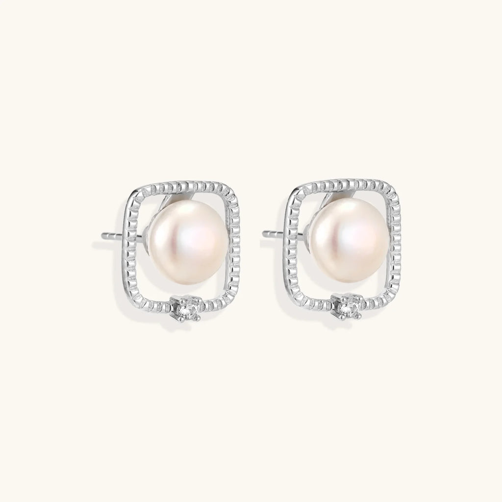 Rhodium-plated silver stud earrings with cushion frame, centered freshwater pearl, and tiny crystal accent