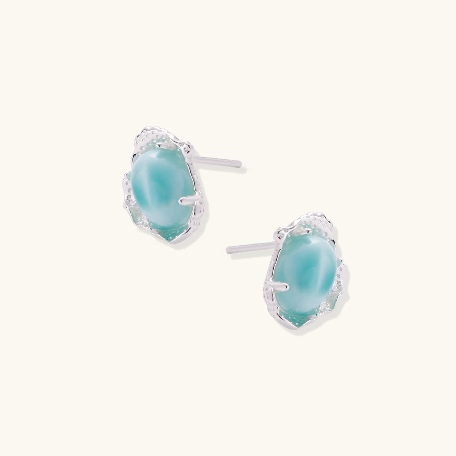 Oval larimar gemstone studs with ornate silver settings showing natural turquoise marbling on cream background