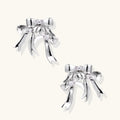 Sculptural bow earrings in polished white gold plate with sparkling zirconia stones and flowing ribbon details