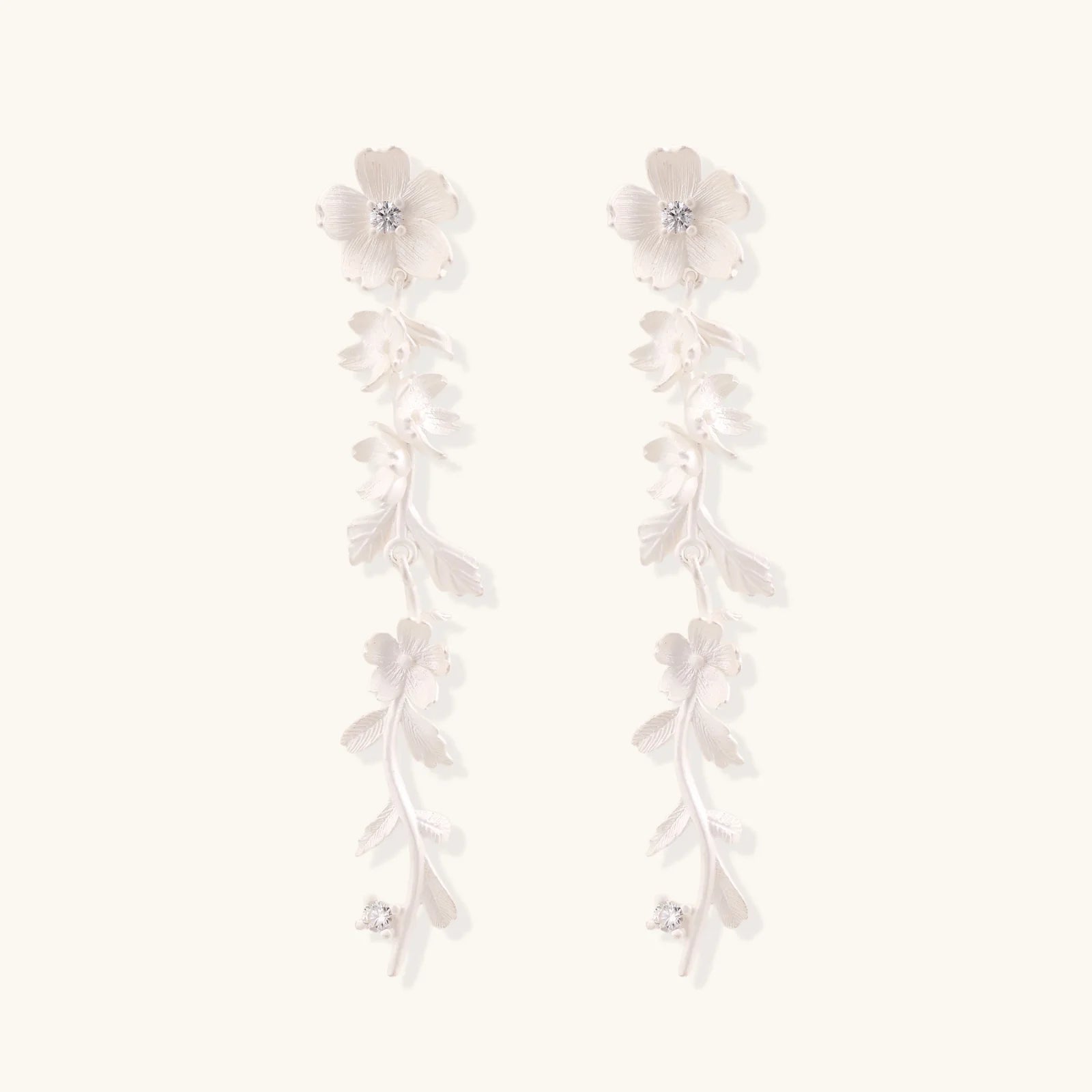Long sterling silver drop earrings with delicate floral vine design and crystal accents on white background