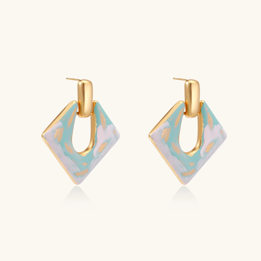 Geometric square enamel earrings with marbled turquoise and lavender pattern, gold U-shaped connector on cream background.