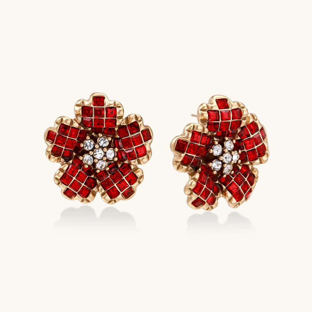 Gold-plated flower studs with burgundy square crystals in petal mosaic and clear center stones on beige background.