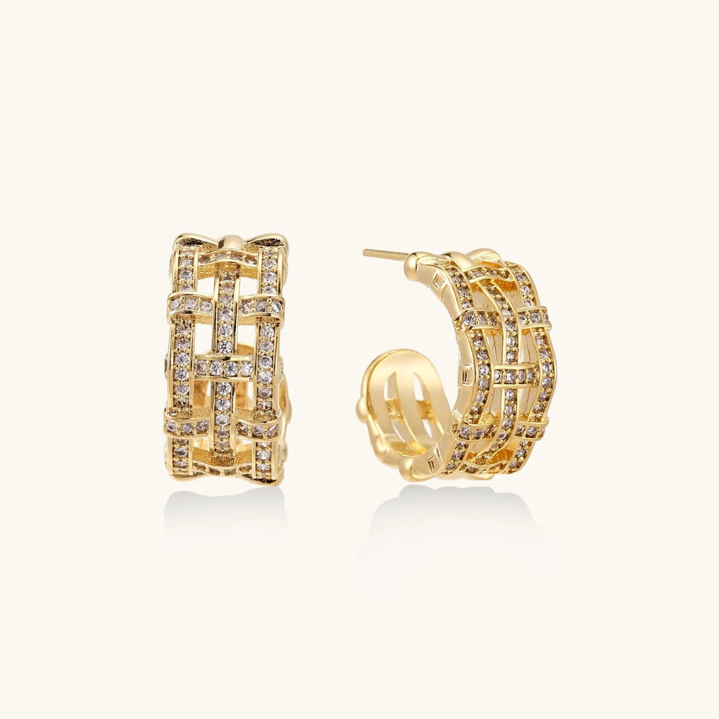Gold-plated geometric hoop earrings with basket-weave lattice design and pavé crystal accents on cream background