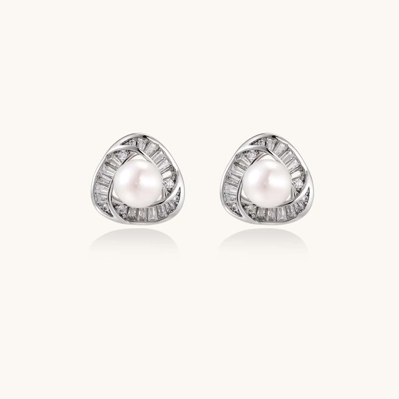 Triangular white gold plated stud earrings with central freshwater pearl and baguette-cut stones on white background