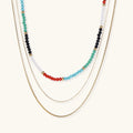Multi-strand necklace with rainbow quartz beads and gold-plated chains on beige background