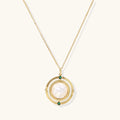 Gold pendant necklace with circular orbital design, iridescent mother-of-pearl center, and green zirconia accents