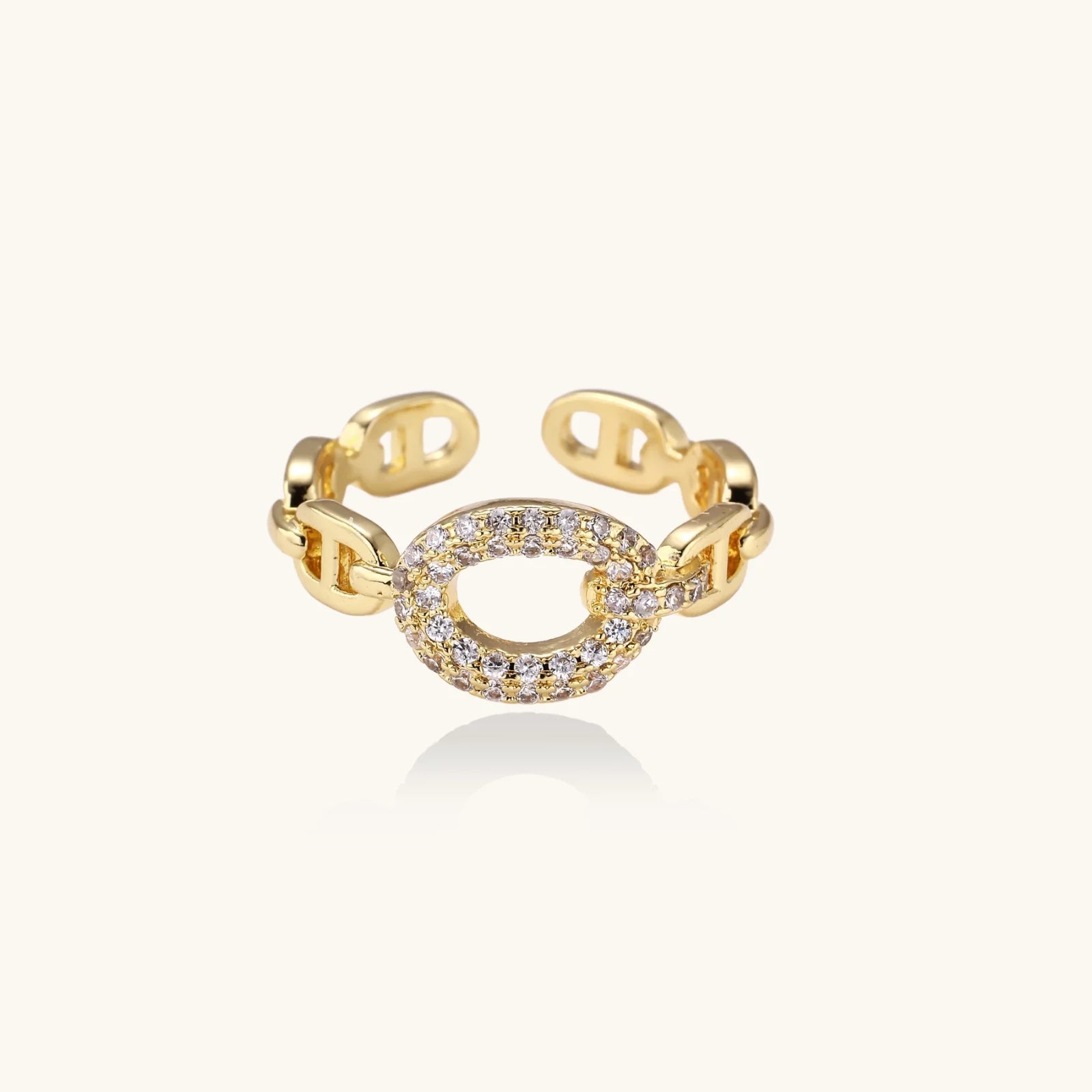 Gold-plated brass chain link ring with one oval CZ-pavé segment on cream background, adjustable cuff style.