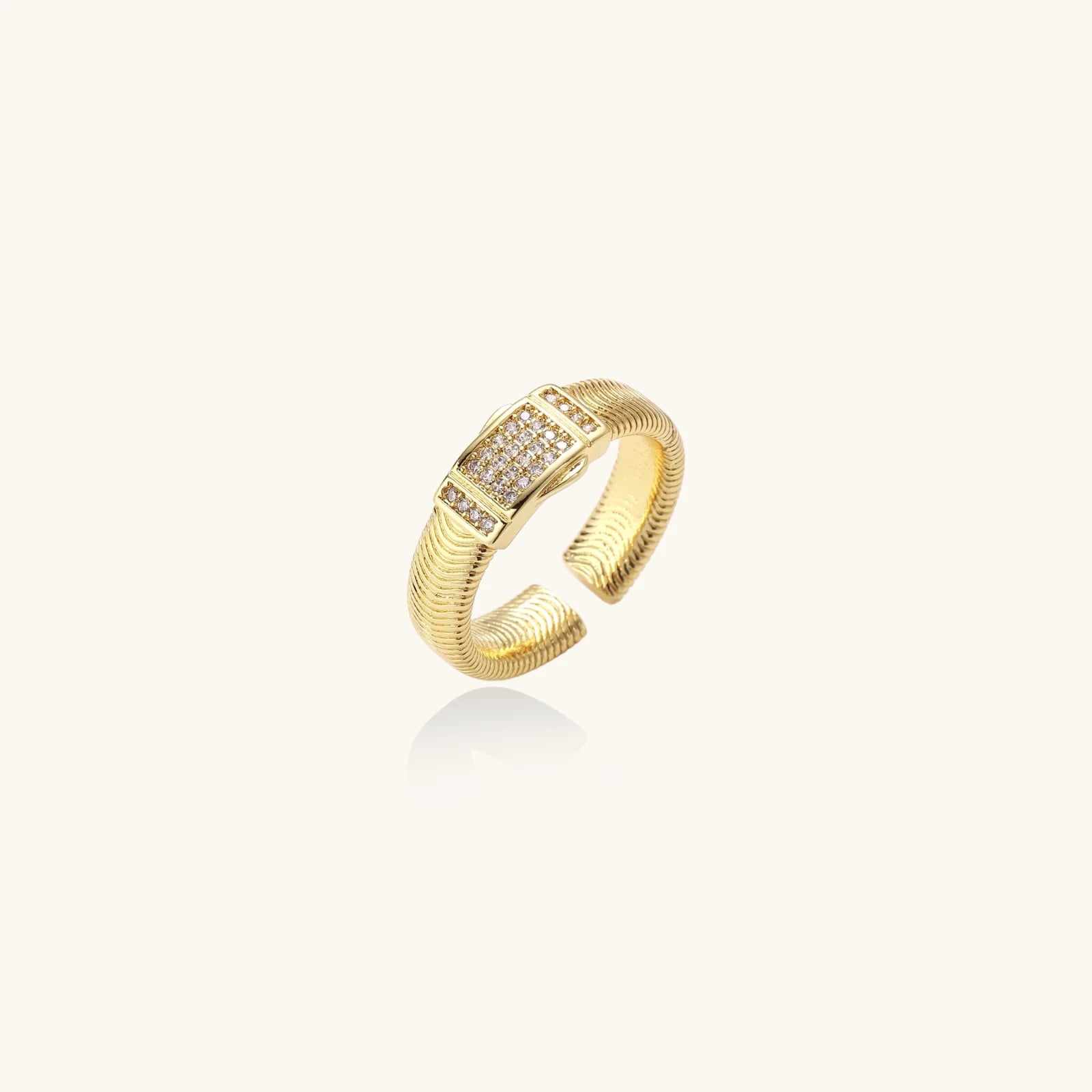 Gold-plated adjustable ring with ribbed band and rectangular pavé cubic zirconia panel on white background.