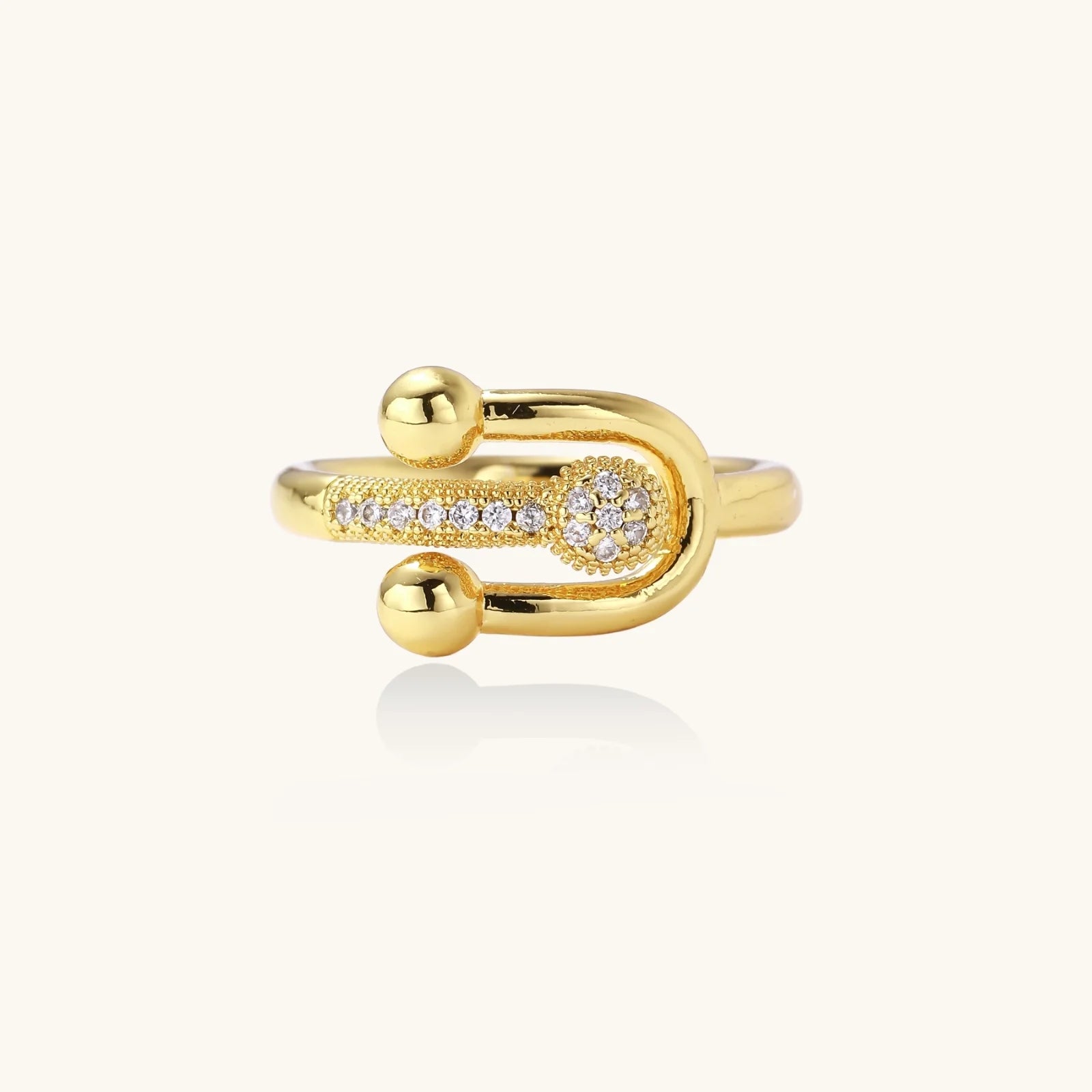 Gold-plated brass ring with safety pin design featuring pavé cubic zirconia stones and dual sphere ends
