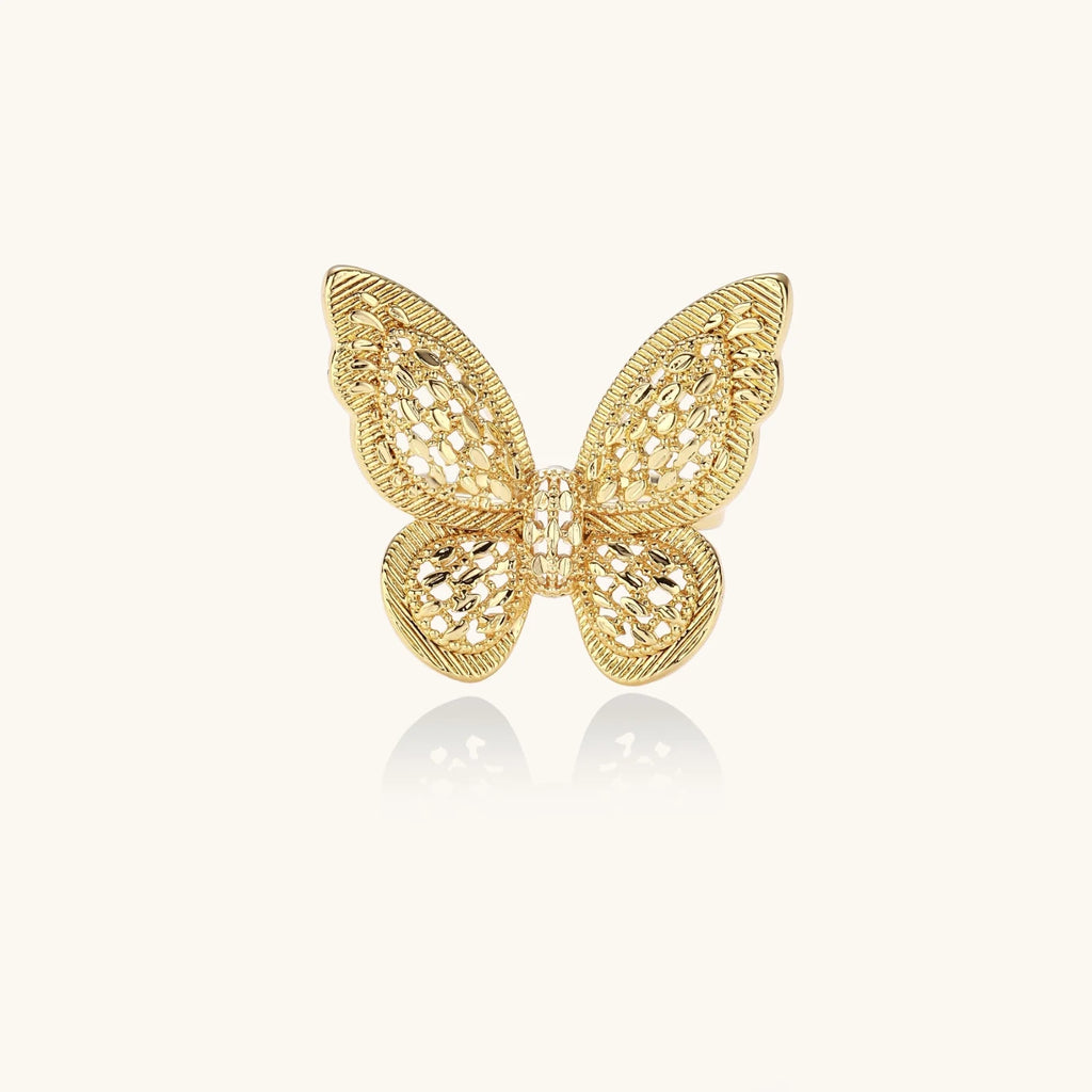 Intricate gold-plated butterfly ring with filigree cutout wings and adjustable band on white background.