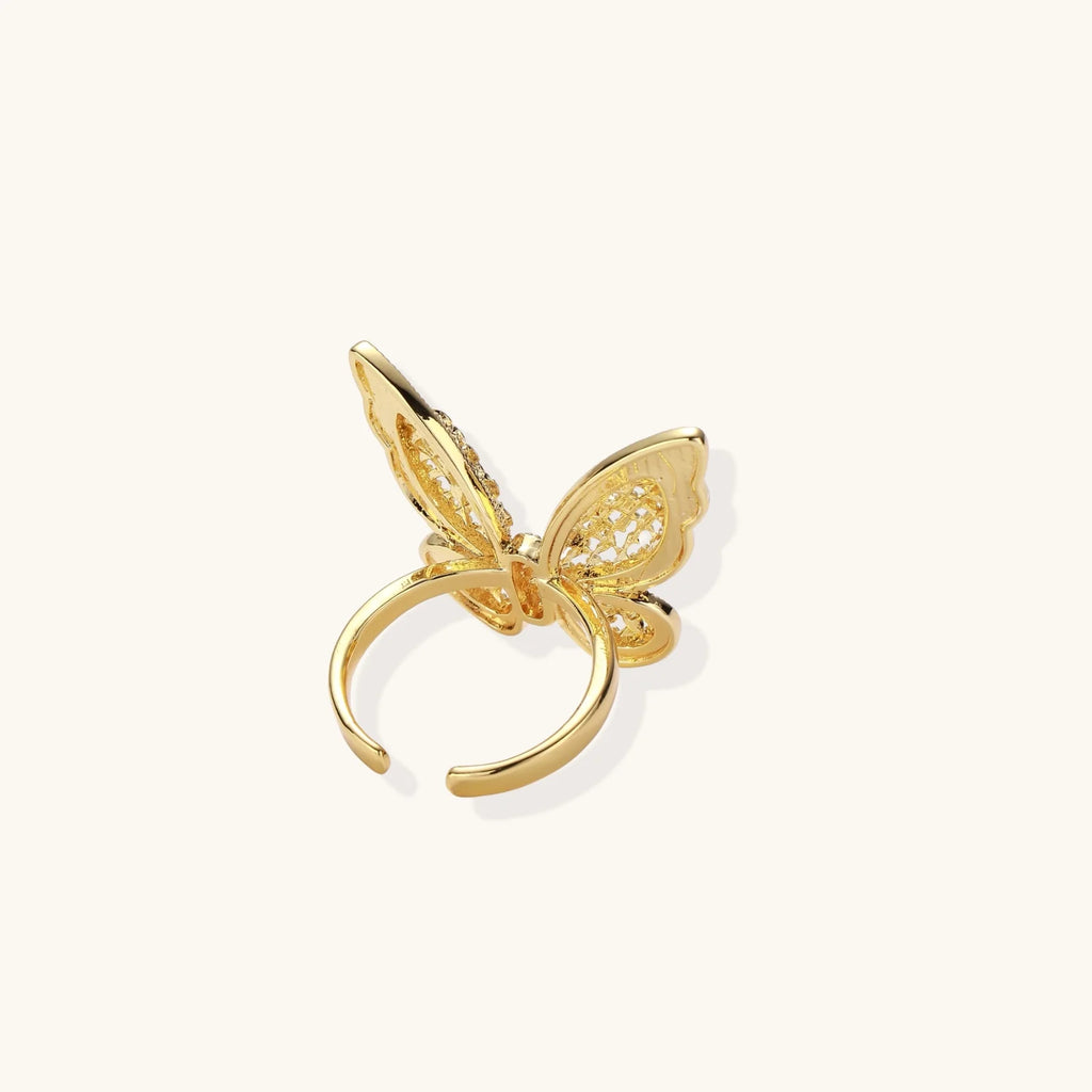 Intricate gold-plated butterfly ring with filigree cutout wings and adjustable band on white background.