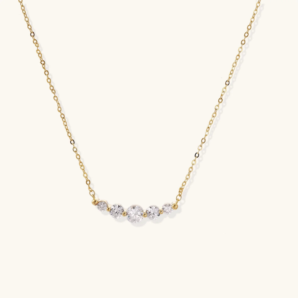 Delicate 14K gold-plated necklace with five graduated zirconia stones arranged in a curved arc on fine chain