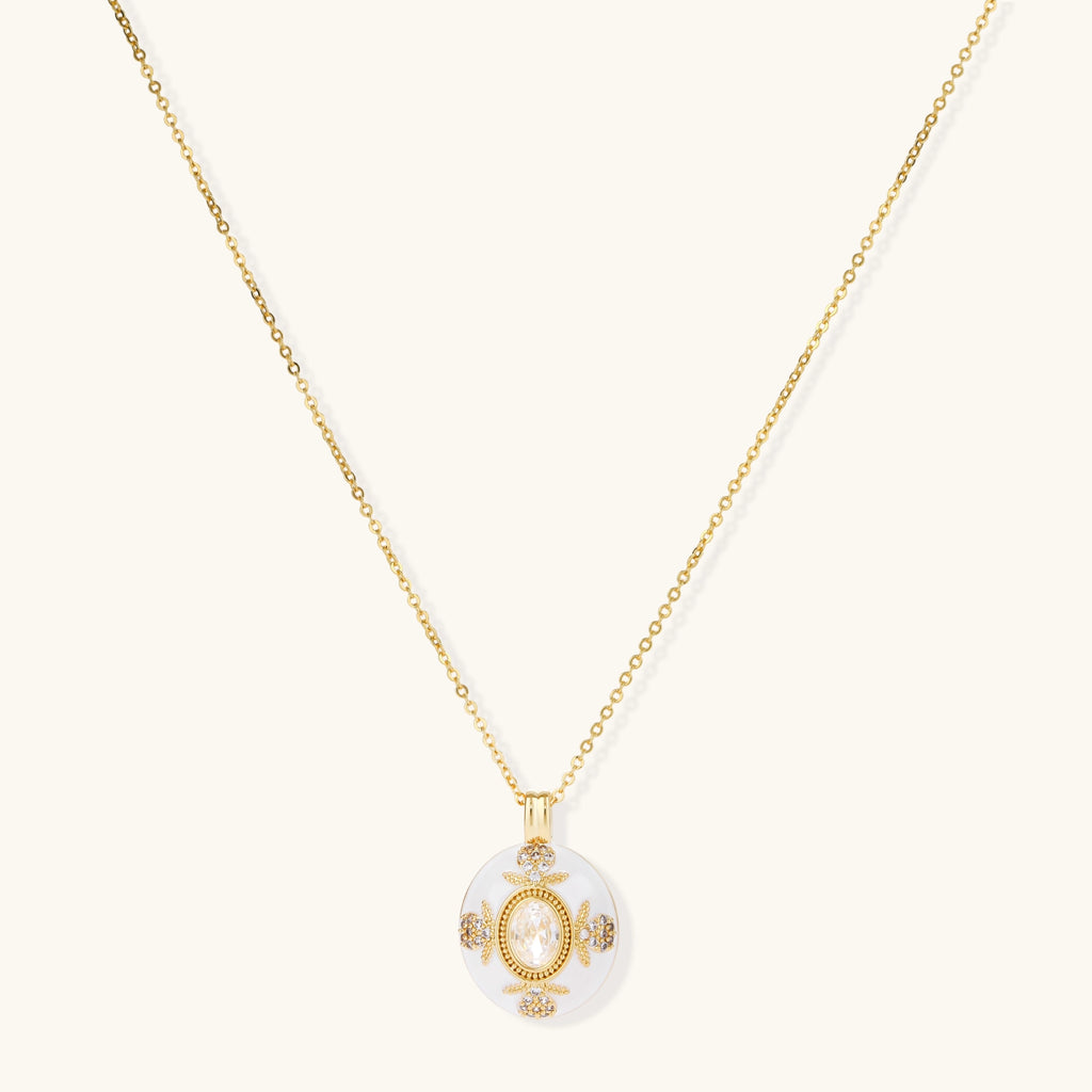 Gold-plated necklace with circular white enamel pendant featuring central zirconia stone and ornate decorative details